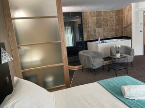 A hotel room with a bed, two chairs, a small table, a sink, and a shower area. - Hotel-Restaurant Les Oliviers (Loriol-sur-Drome)