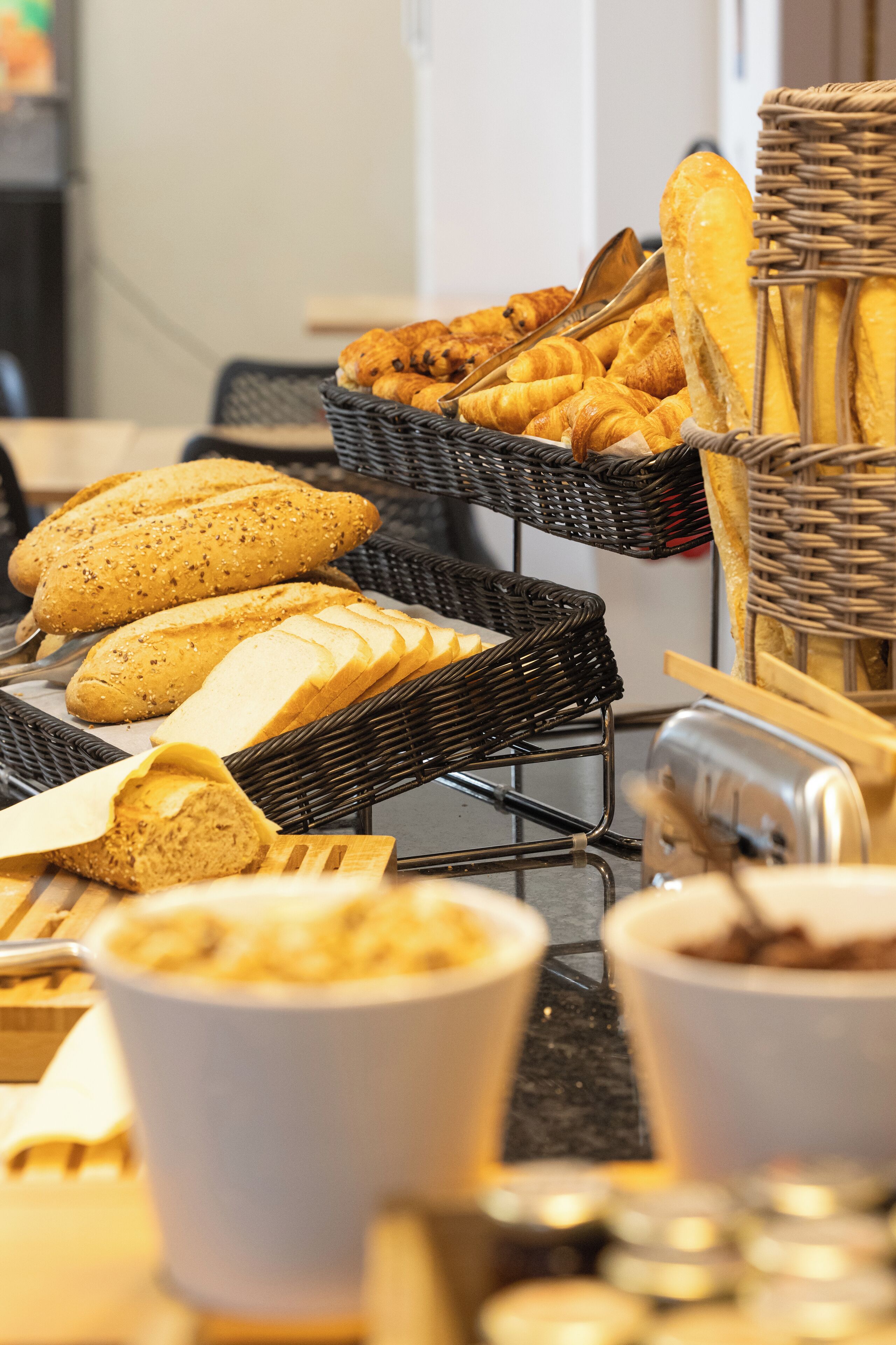 Un buffet de petit-déjeuner proposant une variété de pains et de viennoiseries présentés dans des paniers en osier.