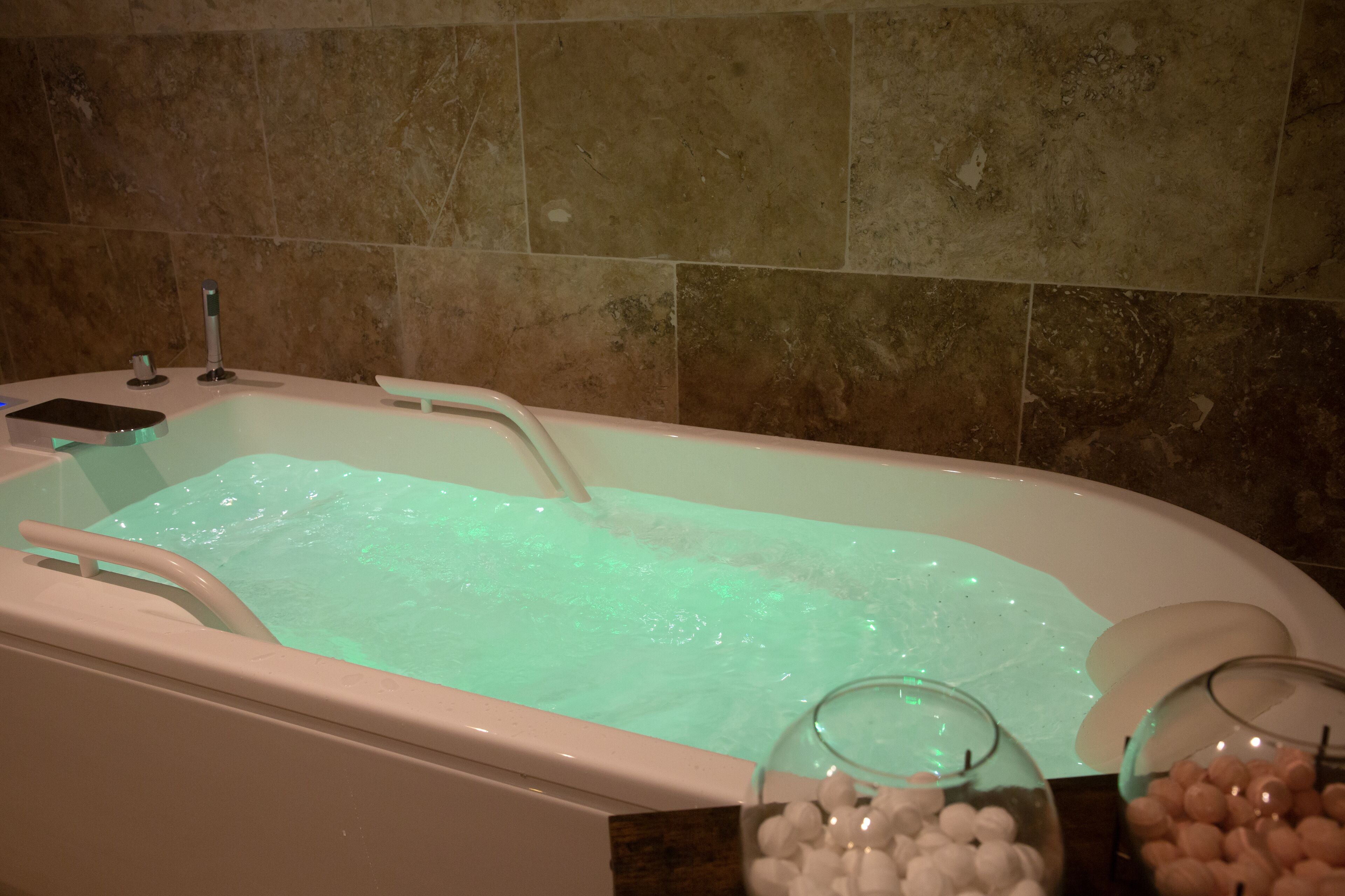 Una bañera con mampara de vidrio y un teléfono inteligente en el borde.