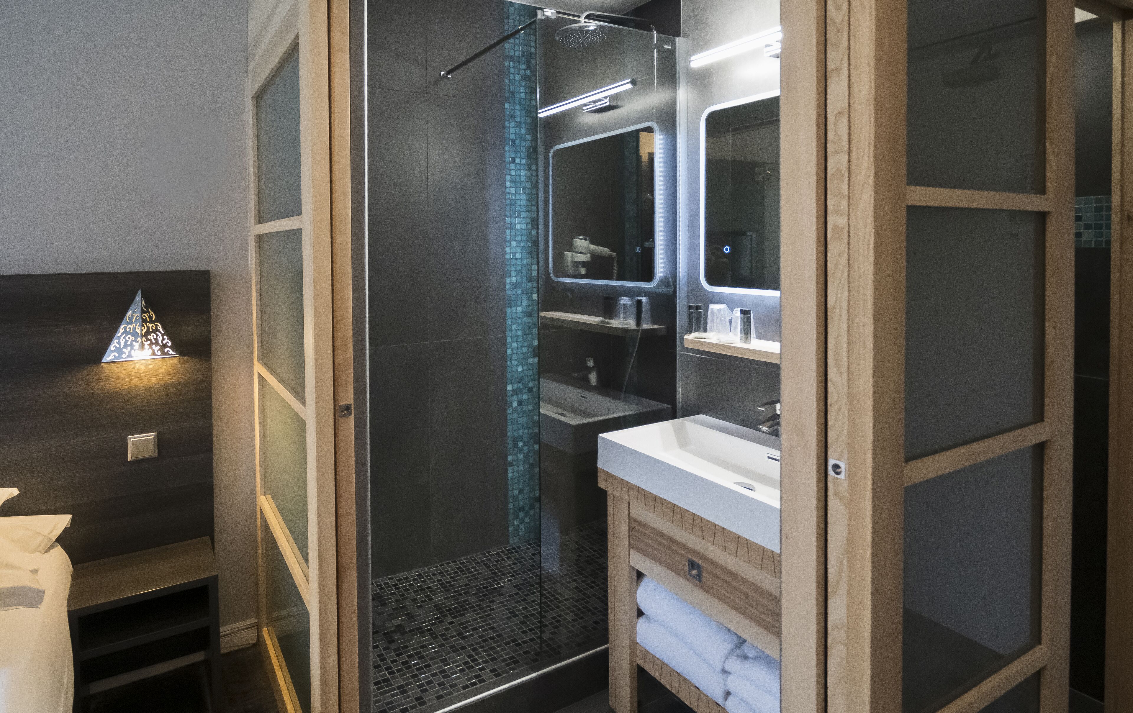 Un baño moderno con ducha de vidrio, tocador con espejo y perchero para toallas.