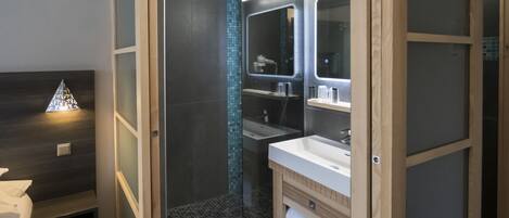 Un baño moderno con ducha de vidrio, tocador con espejo y perchero para toallas.