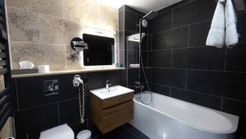 Et moderne badeværelse med badekar, toilet og vaskemøbel.