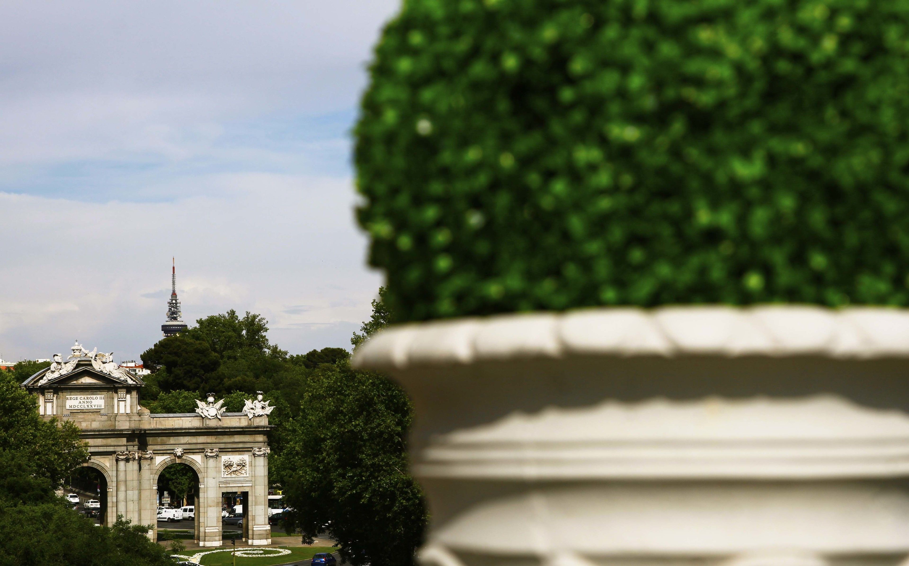 A historic archway with inscriptions, surrounded by lush greenery and a clear sky.