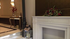 A hotel lobby with a white fireplace, a table with a vase of flowers, and a decorative lantern. - Boutike Cibeles (Madrid)