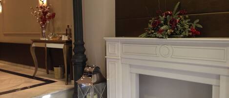 A hotel lobby with a white fireplace, a table with a vase of flowers, and a decorative lantern.
