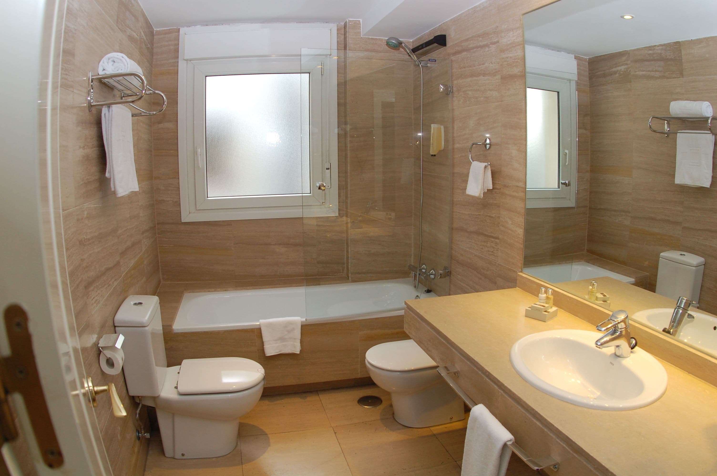 Un baño moderno con bañera, dos inodoros, un lavabo y ducha.