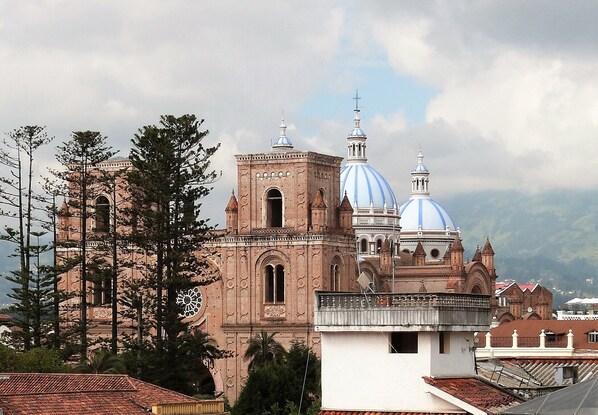 A historic church with large blue domes and a bell tower, surrounded by trees and other buildings.
