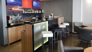 A modern bar area with a bar counter, stools, and a television screen displaying content. - Hotel El Conquistador (Cuenca)