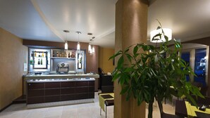Un espace bar moderne avec un comptoir, des étagères remplies de bouteilles et des luminaires suspendus.