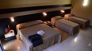 Ein Hotelzimmer mit zwei Betten, einem Nachttisch mit Lampe sowie einem kleinen Tisch mit Telefon und einem roten Gegenstand.