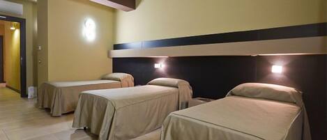 Una habitación de hotel con dos camas individuales, cabecera con iluminación integrada y suelo de baldosas.