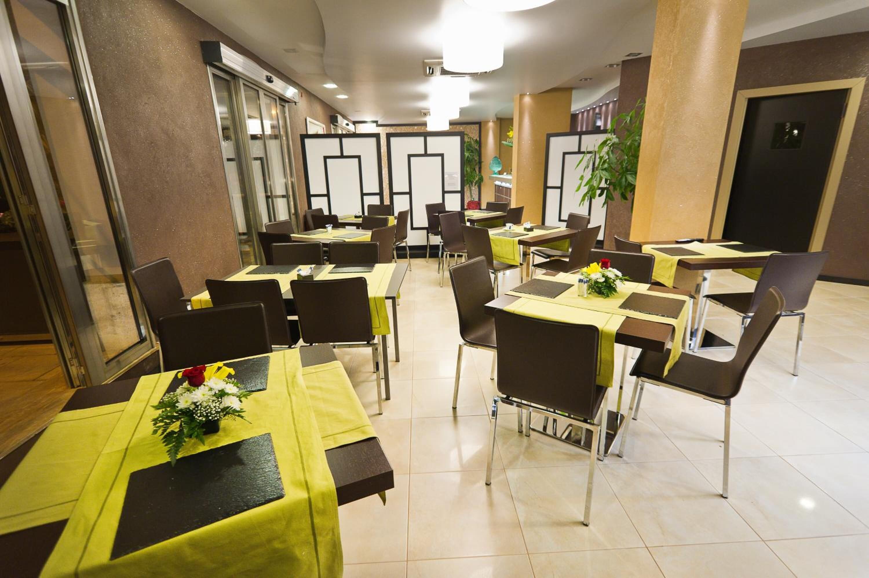 Comedor con mesas dispuestas con manteles amarillos y sillas, con un diseño moderno y una paleta de colores neutros.