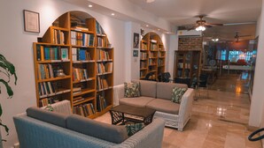 Une bibliothèque spacieuse, dotée d’étagères, d’un canapé et d’un ventilateur de plafond.
