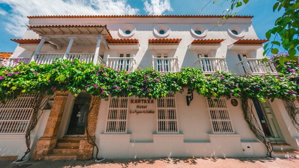Un hôtel à la façade blanche, doté de nombreux balcons et d’une entrée abritée.