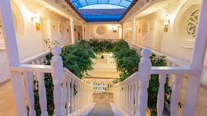 A grand staircase with a glass ceiling, white balustrades, and lush greenery. - Hotel Kartaxa Cartagena (Cartagena)