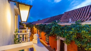A narrow street with a white railing, a lantern, and a building with a tiled roof and ivy-covered walls. - Hotel Kartaxa Cartagena (Cartagena)