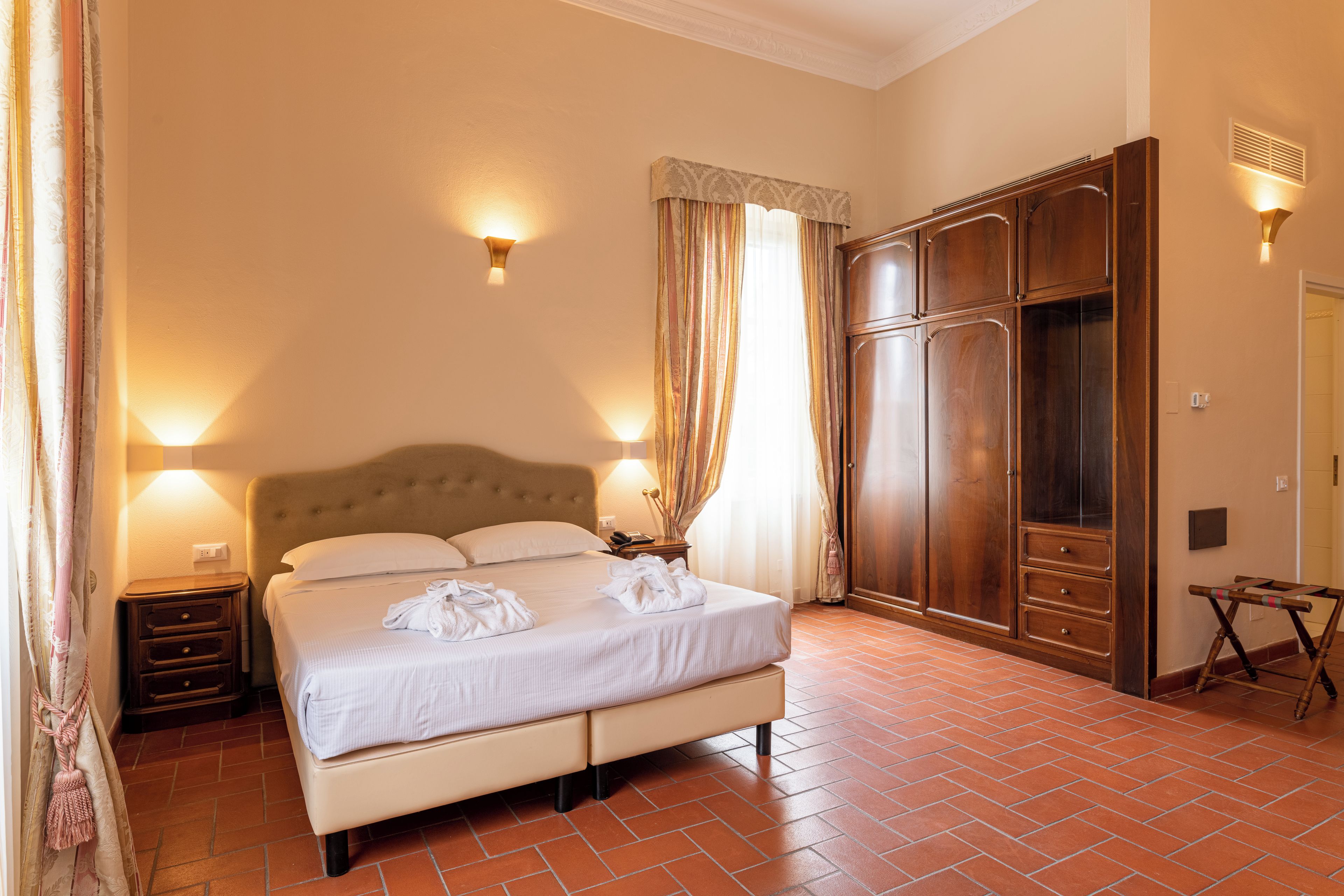 Une chambre d’hôtel comprenant un lit, des tables de chevet, une armoire et une petite table avec une chaise.