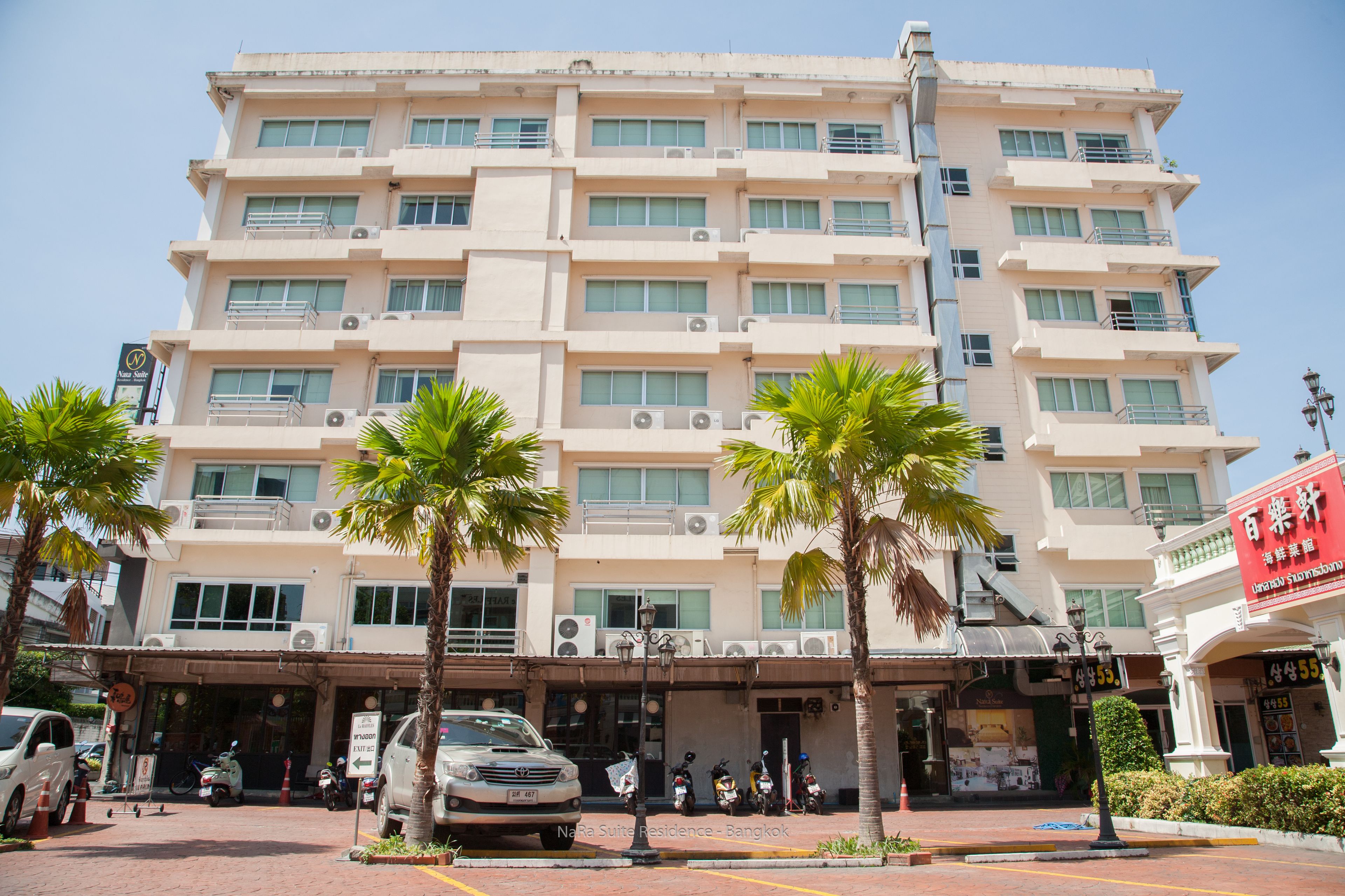 A multi-story hotel with a flat facade, air conditioning units, and a signboard.