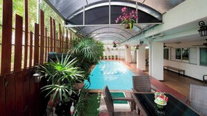 Área de piscina coberta com assentos e plantas em vasos.