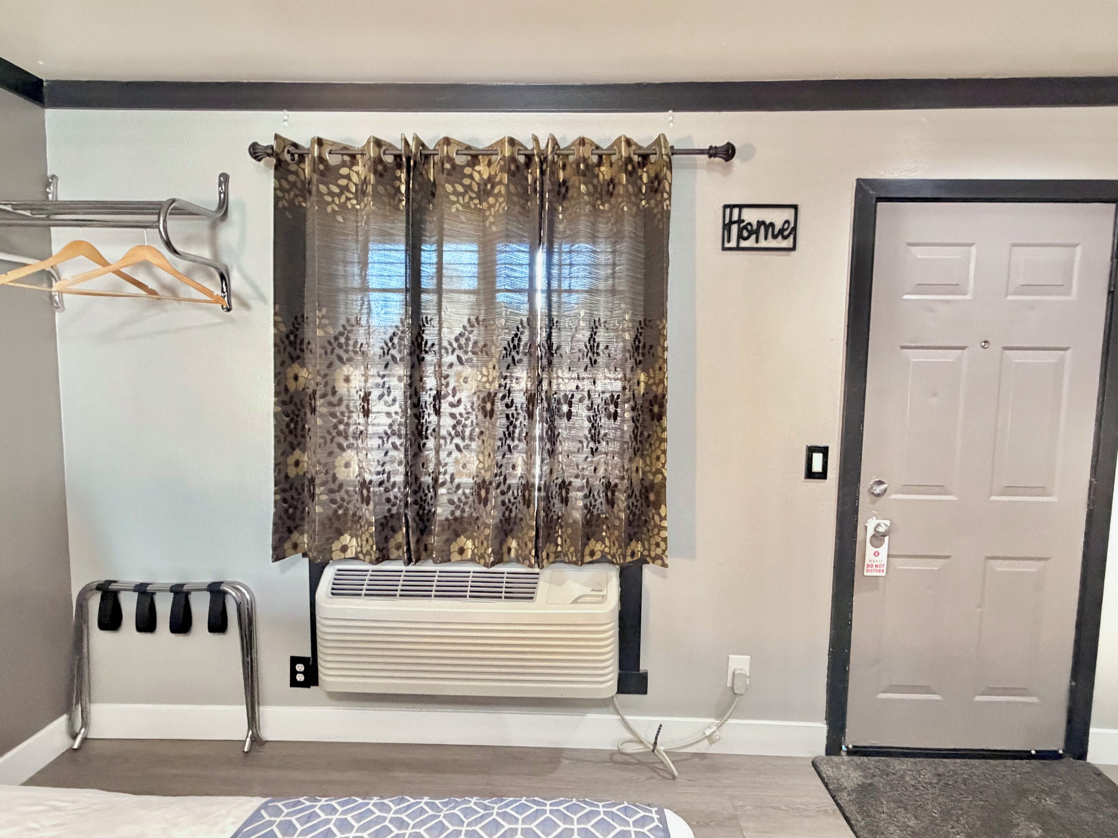 A room with a radiator, a door, a window with a curtain, and a sign that says 'Home'.