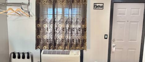 A room with a radiator, a door, a window with a curtain, and a sign that says 'Home'.