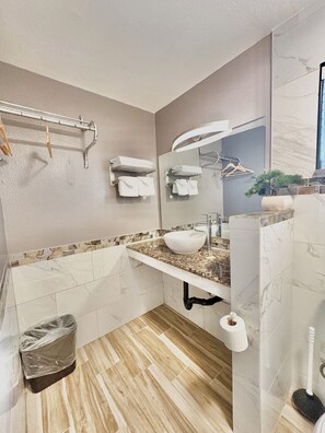 A modern bathroom with a marble sink, towel rack, and a mirror. - Cascade Lodge Boutique (Bend)