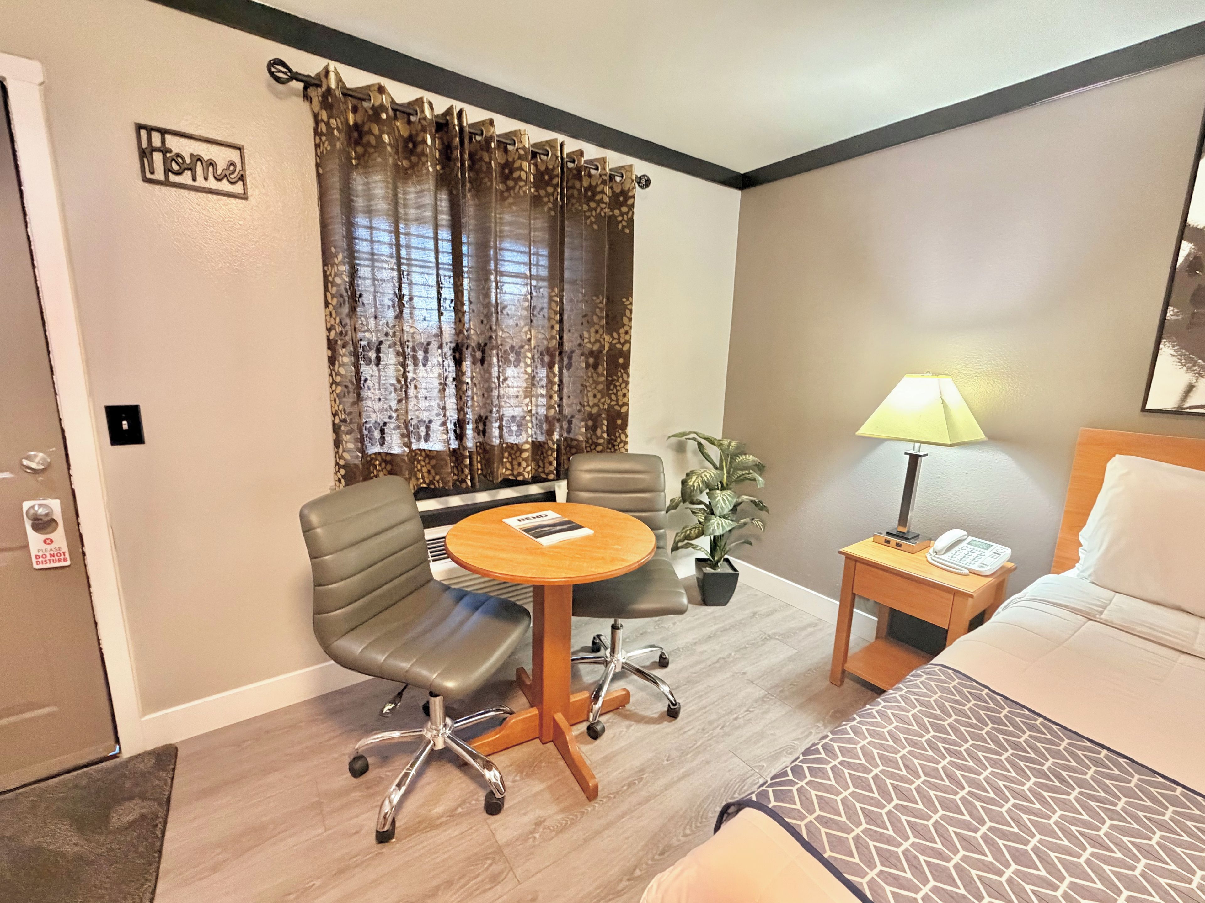 Une chambre d’hôtel avec un lit, un bureau avec une chaise, une lampe et une plante.
