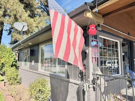 A house with a satellite dish, an American flag, and a red hanging pot.
