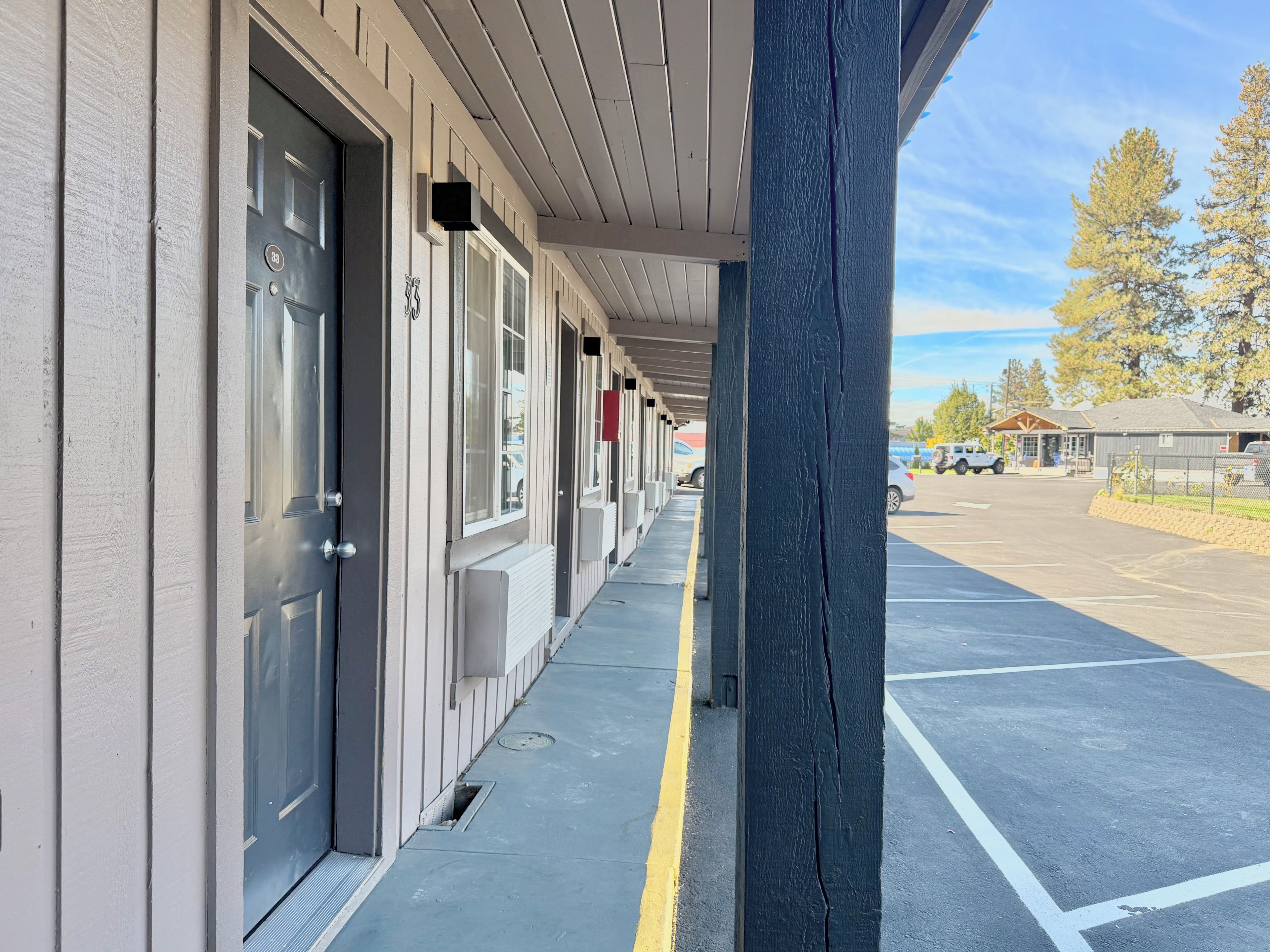 Une rangée de chambres d’hôtel, chacune dotée d’une porte individuelle, un passage couvert et un parking.
