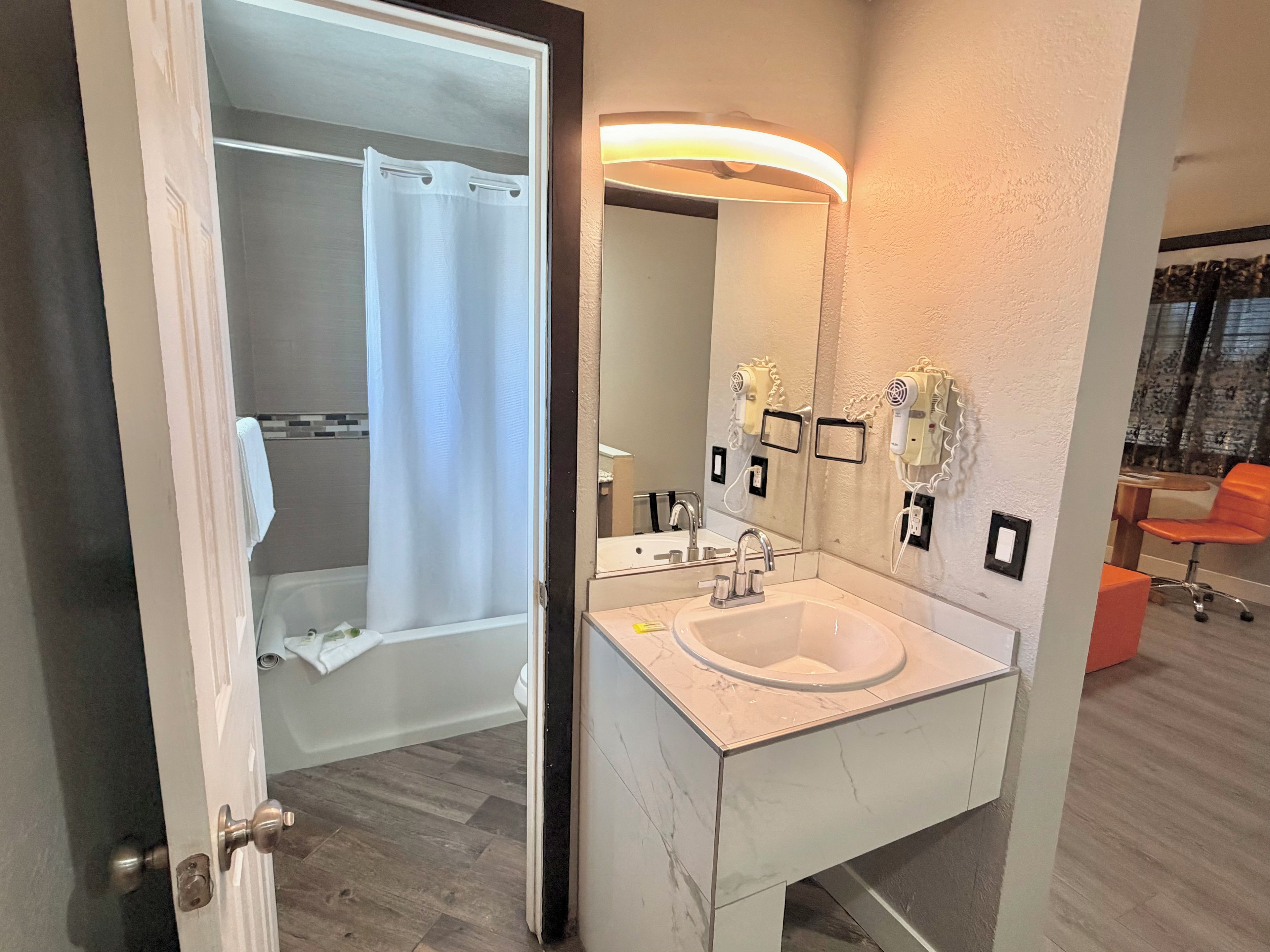 A modern bathroom with a white sink, a mirror, and a shower area.