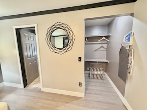 A room with a door, a wall-mounted mirror, a hanging towel rack, and a shelf unit. - Cascade Lodge Boutique (Bend)