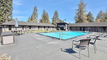 A swimming pool with lounge chairs and a building with a dark exterior.