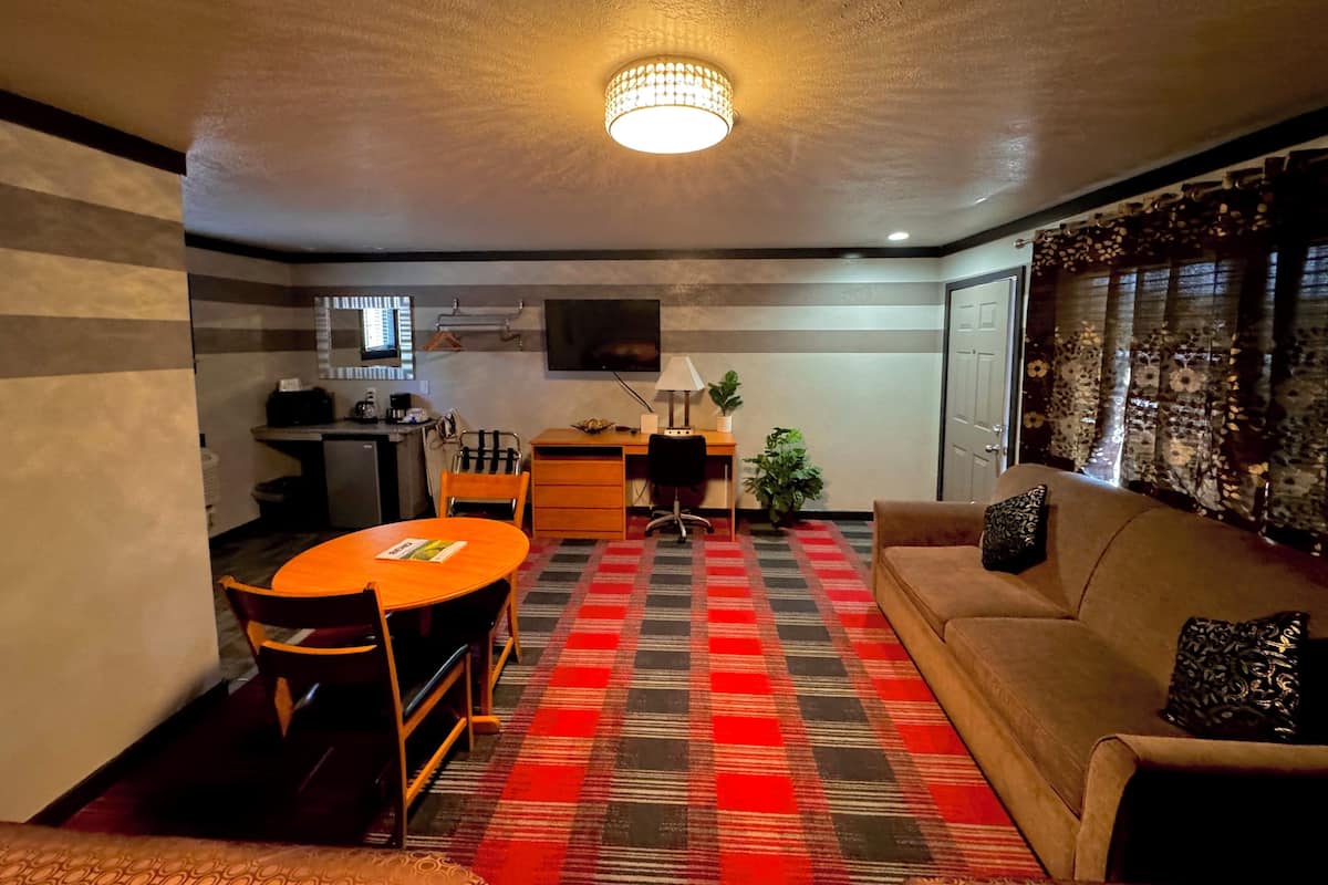 A compact living space with a dining table, sofa, and a television mounted on the wall.