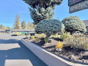 A parking lot with a sign indicating a heated pool, surrounded by landscaped areas with various shrubs and trees. - Cascade Lodge Boutique (Bend)