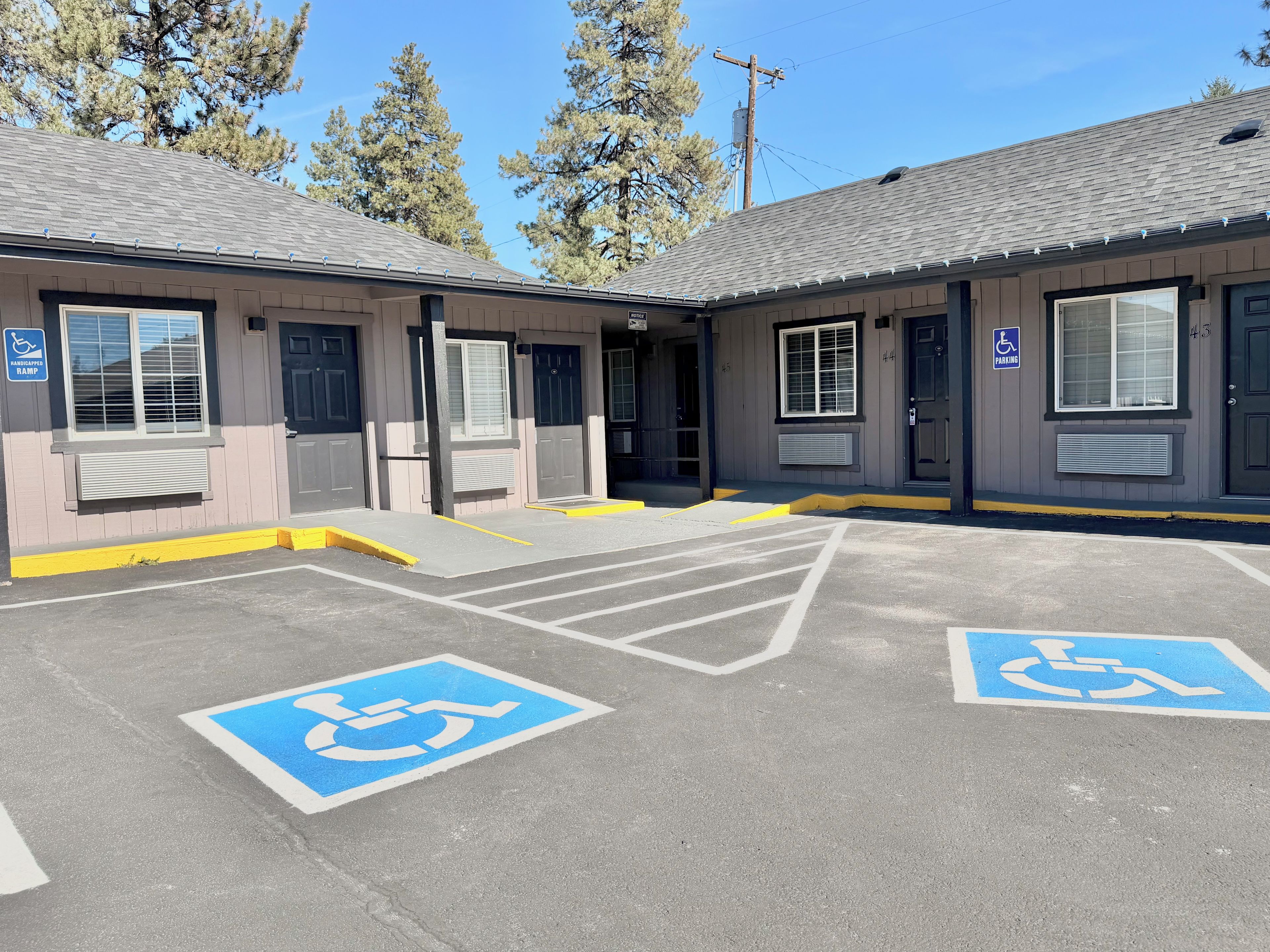 Un bâtiment doté de deux entrées accessibles, de places de stationnement clairement indiquées et offrant une vue sur un ciel dégagé.