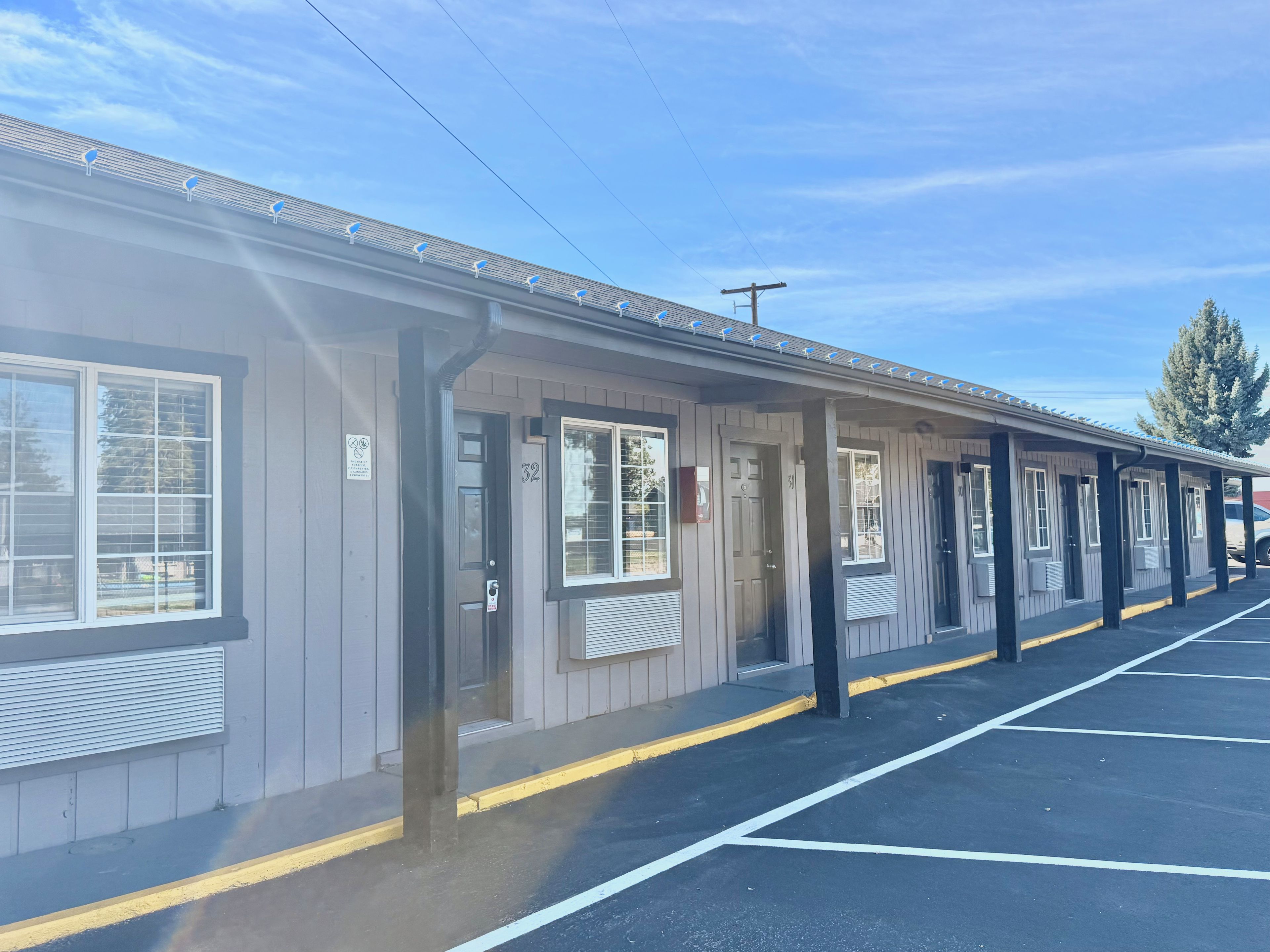 A motel with individual rooms, a covered parking area, and a clear sky.