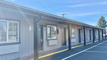 A motel with individual rooms, a covered parking area, and a clear sky.