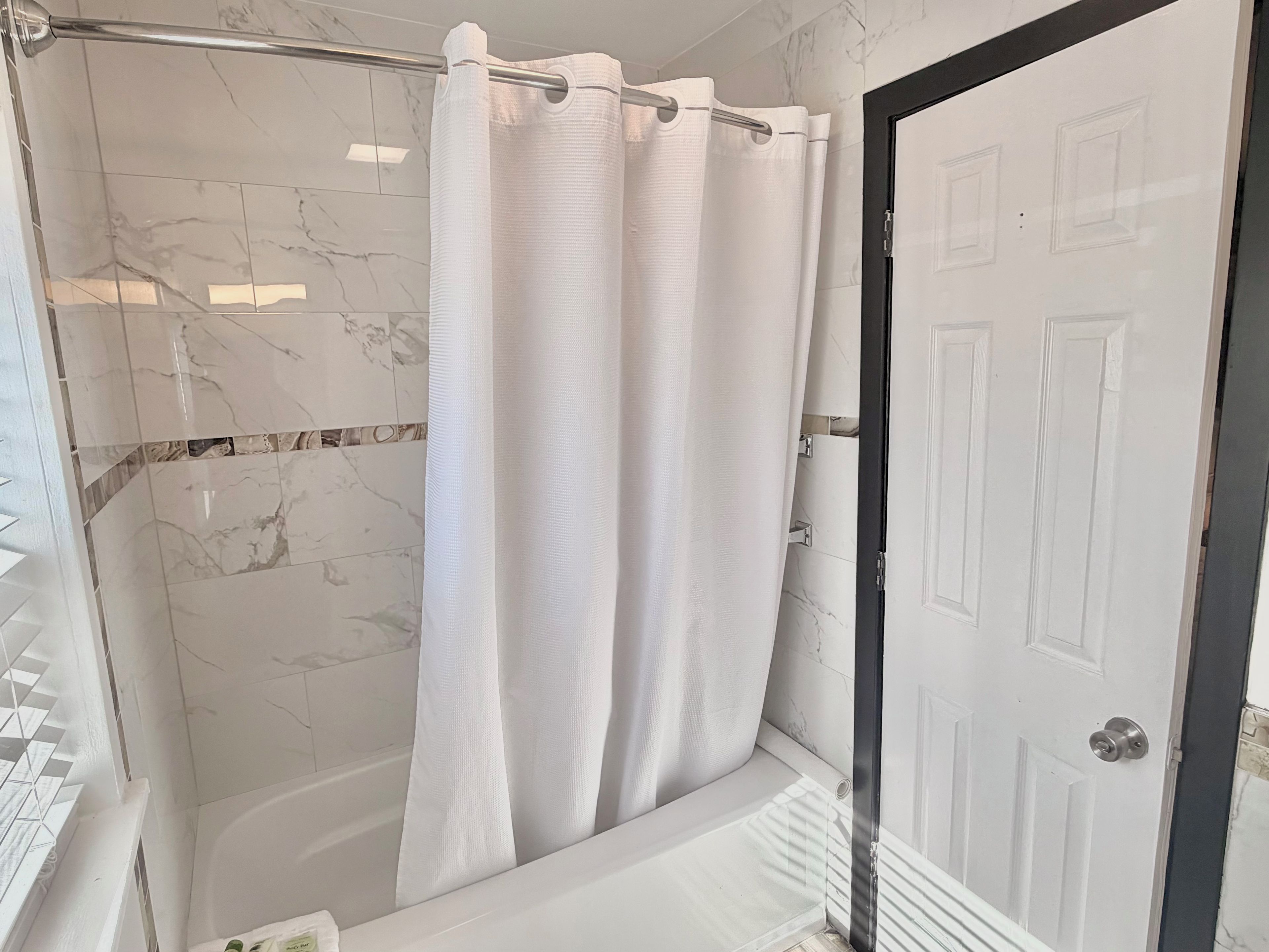 A bathroom with a shower, a bathtub, and a door.