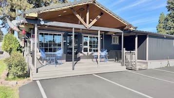 A building with a covered patio area, outdoor seating, and a parking lot.