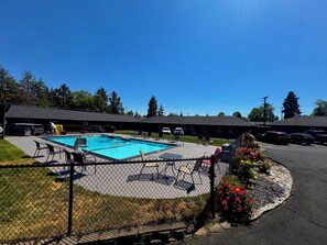 A swimming pool area with lounge chairs and a fenced deck.