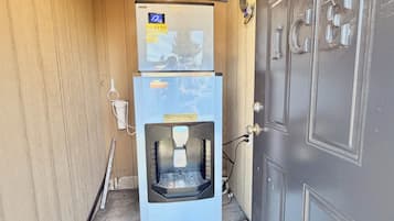 A compact room with a door, a water dispenser, and a small refrigerator.