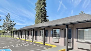 A building with a covered outdoor area, marked parking spaces, and a wheelchair-accessible ramp.