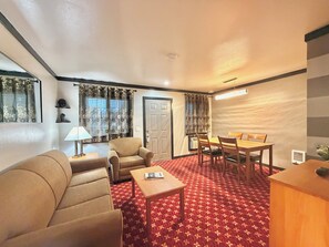A hotel room with a sofa, armchairs, a dining table with chairs, a lamp, and a patterned carpet. - Cascade Lodge Boutique (Bend)