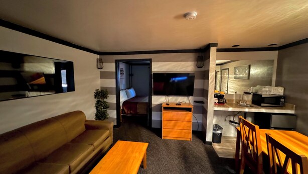A compact living space with a sofa, a wooden table, a kitchenette, and a TV. - Cascade Lodge Boutique (Bend)
