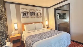 A hotel room with a bed, bedside lamps, a wall-mounted air conditioner, and framed pictures of luxury brands.