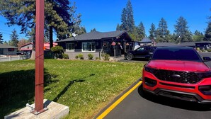 A red car parked in front of a building with a dark roof and a satellite dish. - Cascade Lodge Boutique (Bend)