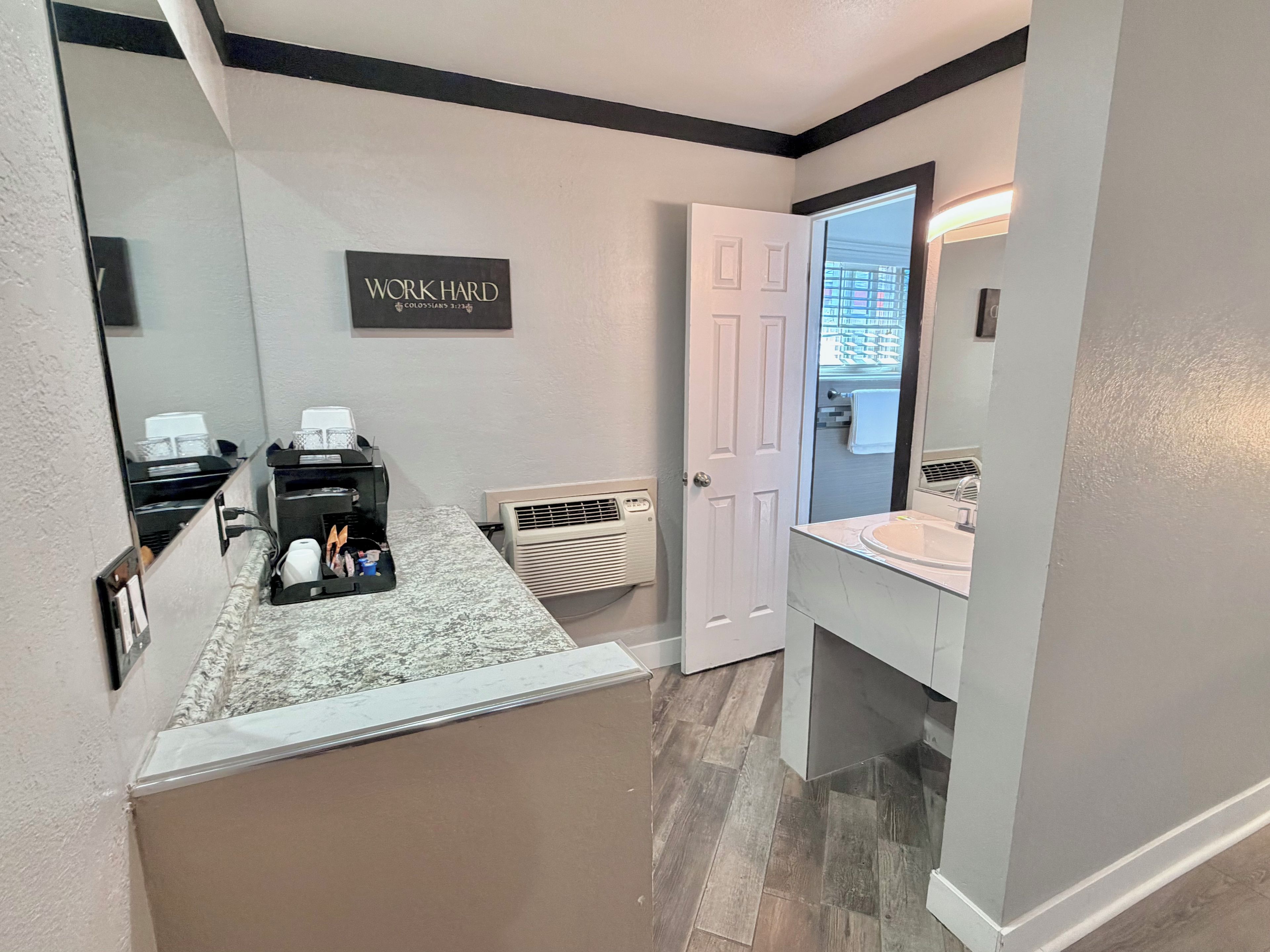 A bathroom with a vanity, a mirror, a towel rack, and a 'WORK HARD' motivational sign.