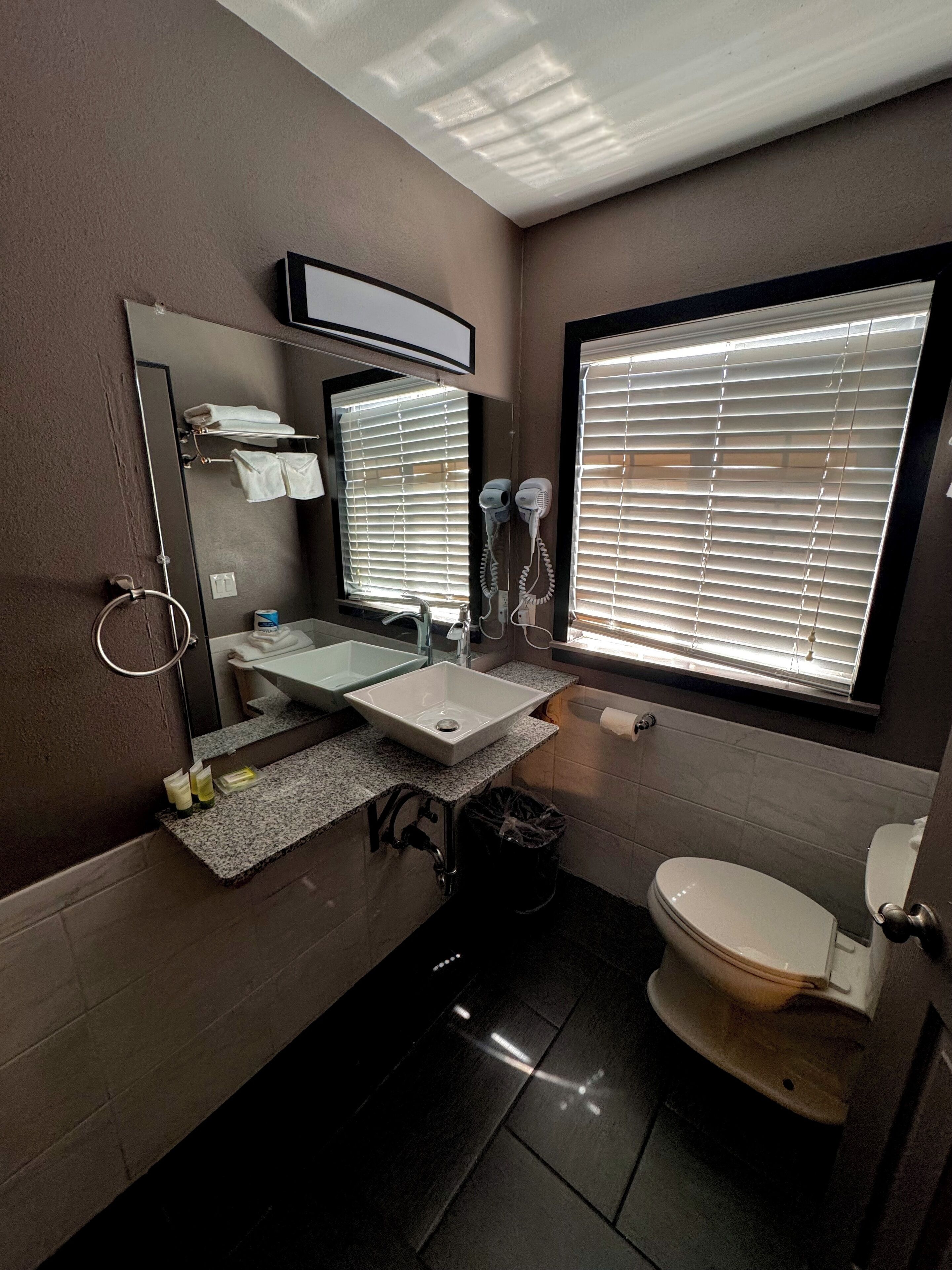 A bathroom with a sink, mirror, towel rack, and toilet.