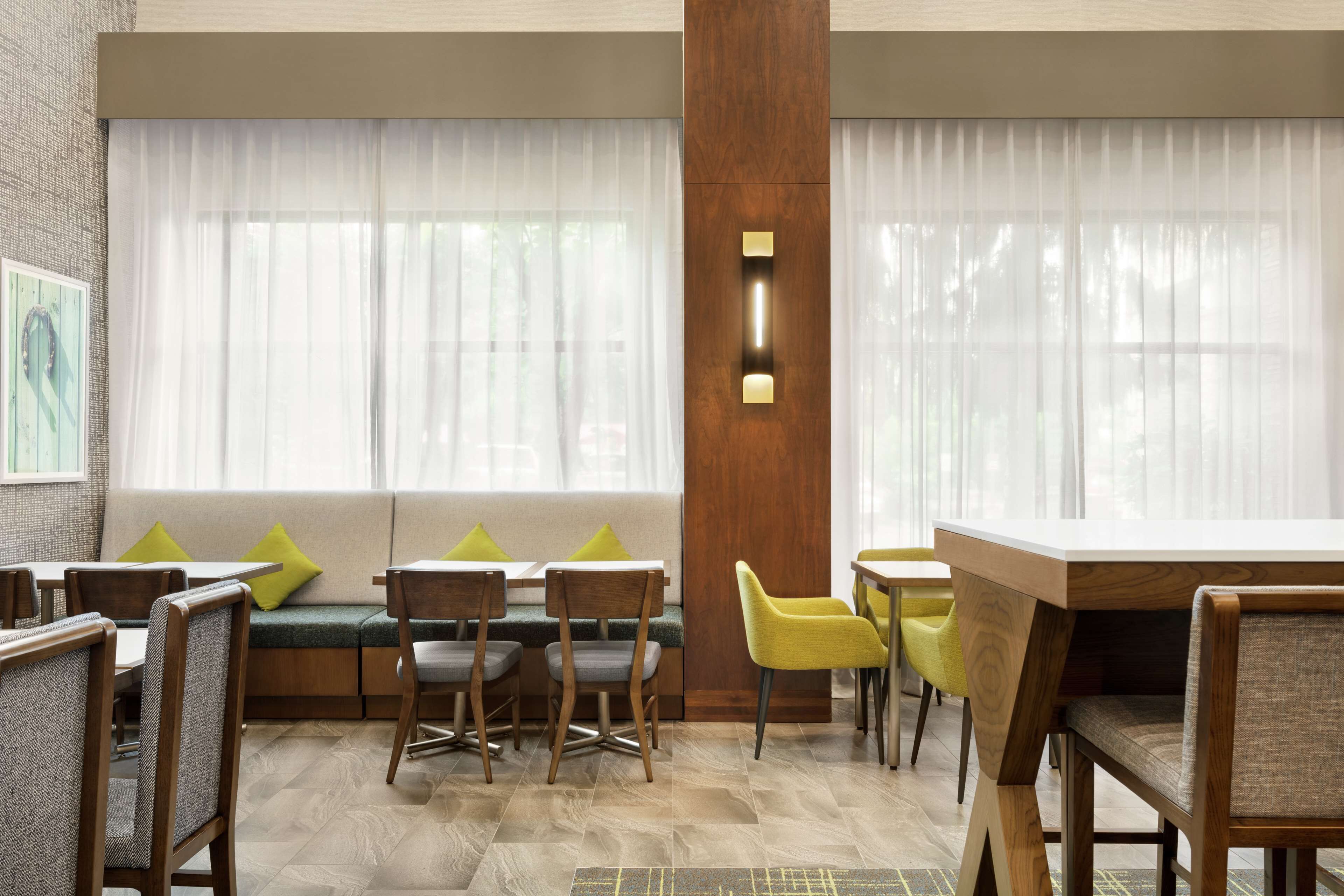 A restaurant with a wooden bench seating area, a high table, and chairs.