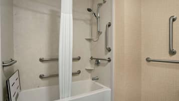 A bathroom with a bathtub, grab bars, and a shower area.